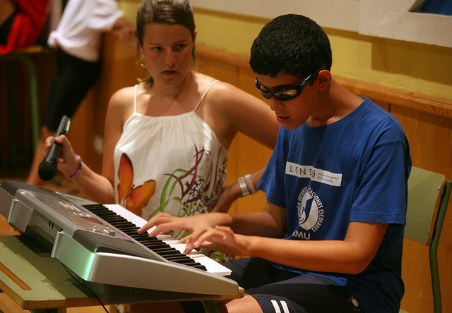 Chico con problemas de visión tocando el piano en clase de música